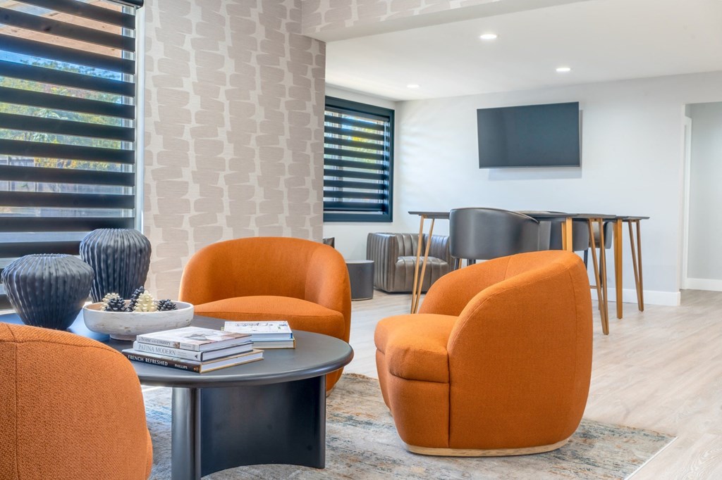 a living room with orange chairs and a table