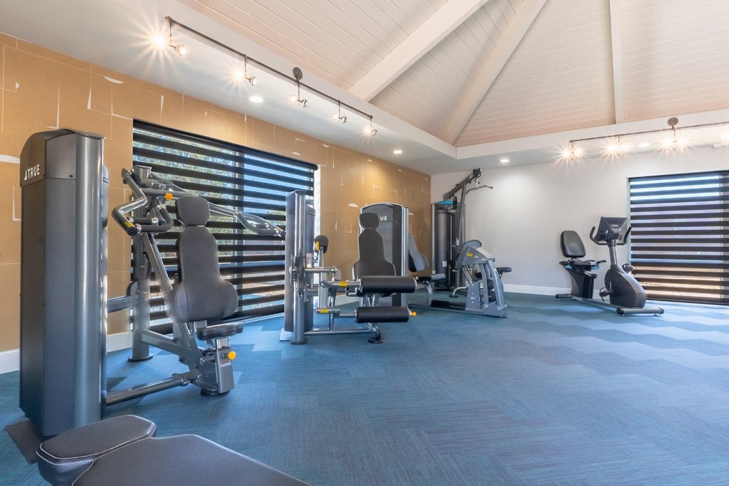 a gym with weights and cardio equipment in a building with white walls