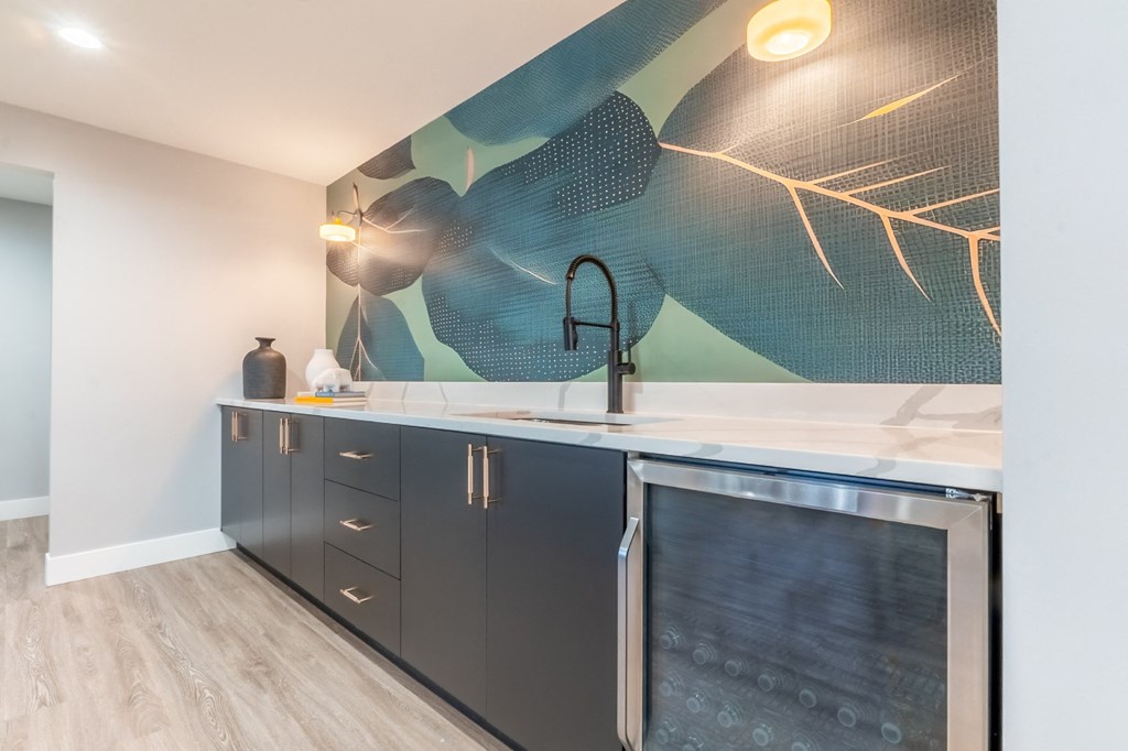 a kitchen with black cabinets and a sink and a painting on the wall