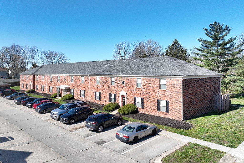 A parking lot with cars in front of a brick building.