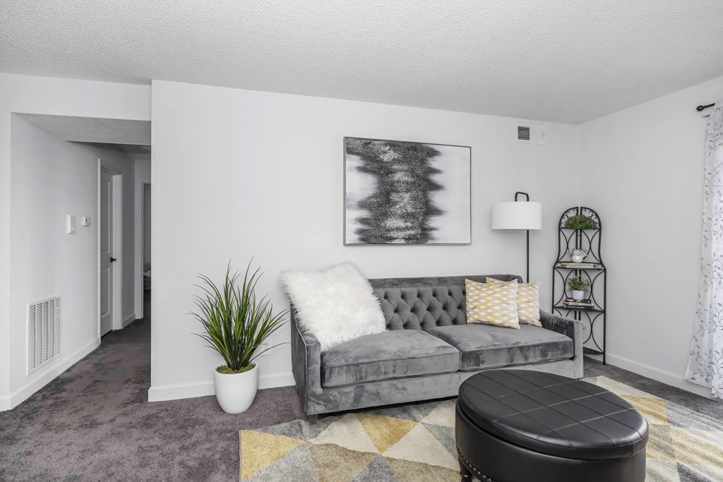 Living room with a gray couch and a black ottoman at Tall Timber Apartments, Ohio, 45241