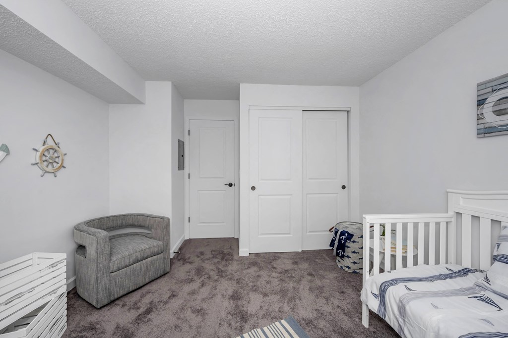 Bedroom with a crib and a chair and a closet at Tall Timber Apartments, Cincinnati
