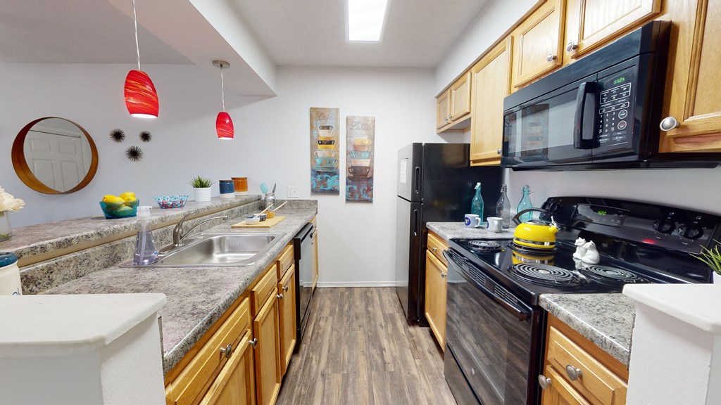a kitchen with granite counter tops and wooden cabinets and black appliances