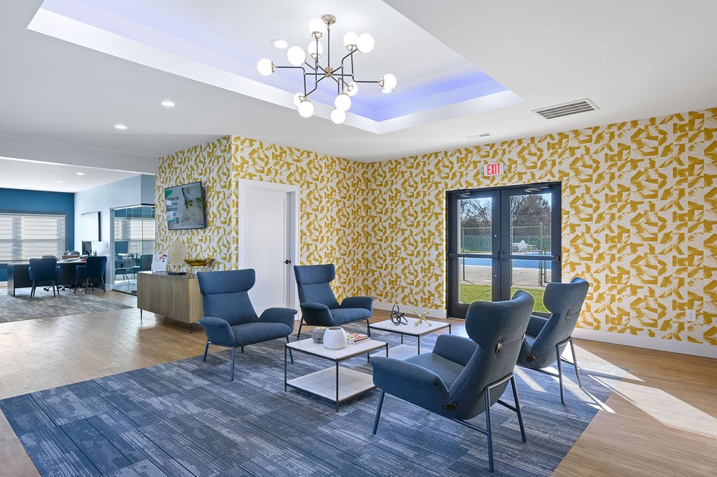 a lobby with blue chairs and yellow wallpaper and a chandelier