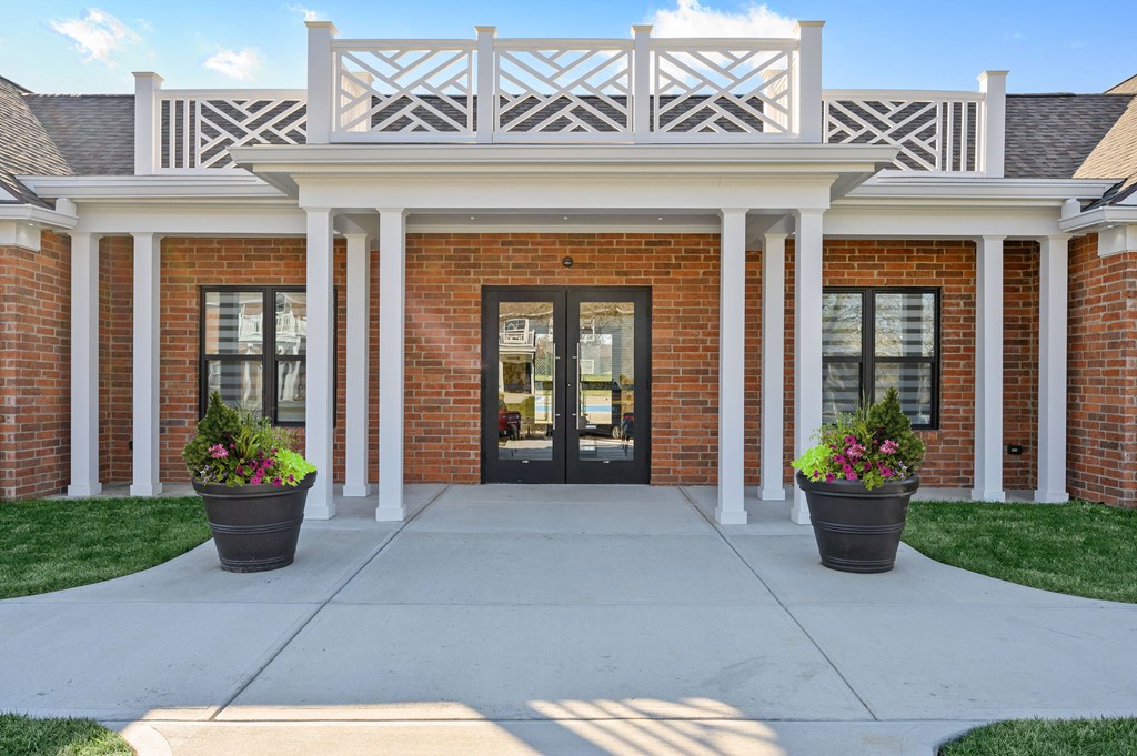 the front door of a brick building with two potted plants