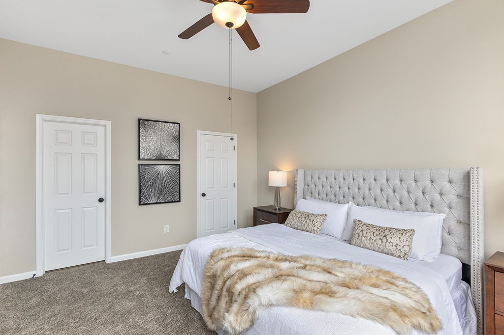 A bedroom with a large bed and a ceiling fan.