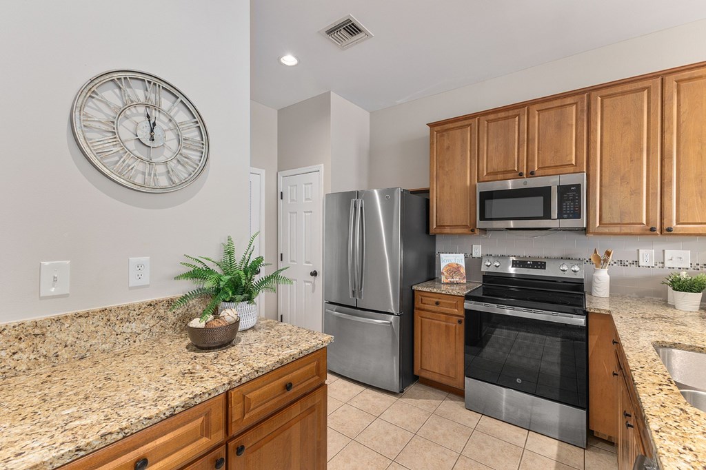A kitchen with granite countertops and wooden cabinets.
