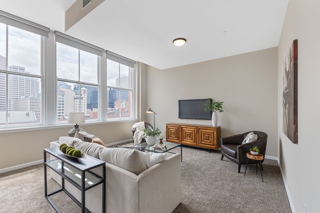 A living room with a grey couch, a black coffee table, a wooden cabinet, and a television.