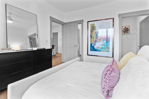 A bedroom with a large bed and a painting on the wall.