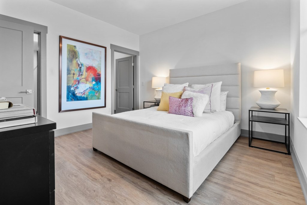 A bedroom with a large bed, a nightstand, and a painting on the wall. at The Ridge Apartments, Cincinnati, OH