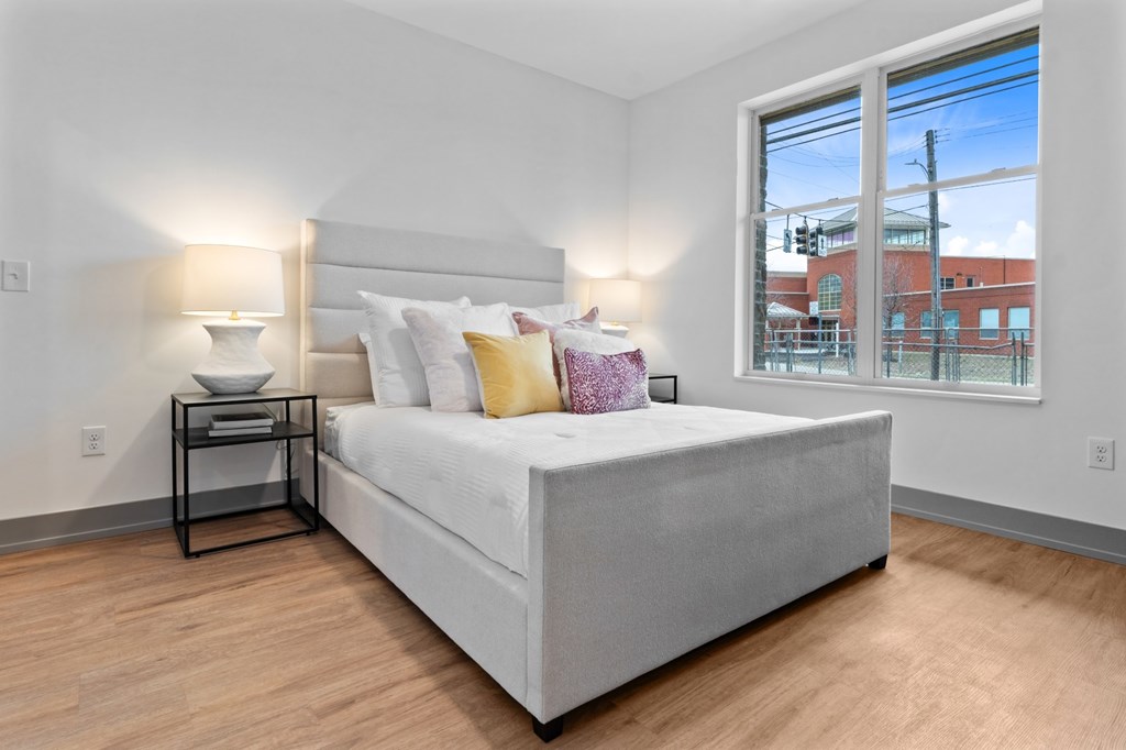 A bedroom with a large bed and a window overlooking a cityscape. at The Ridge Apartments, Ohio