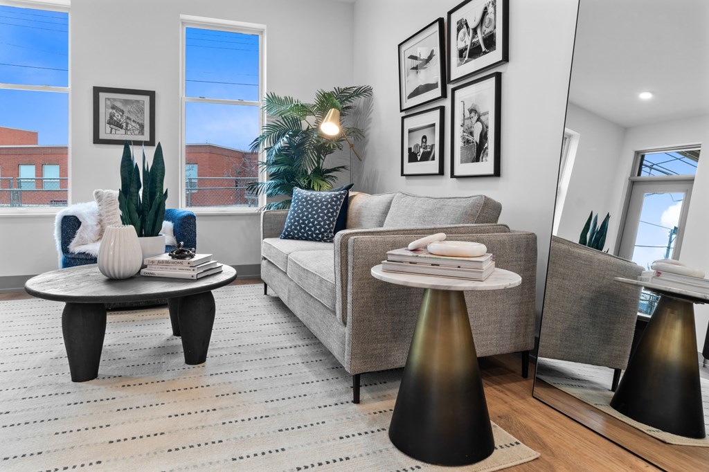 A living room with a grey couch, a coffee table, and a large window. at The Ridge Apartments, Cincinnati