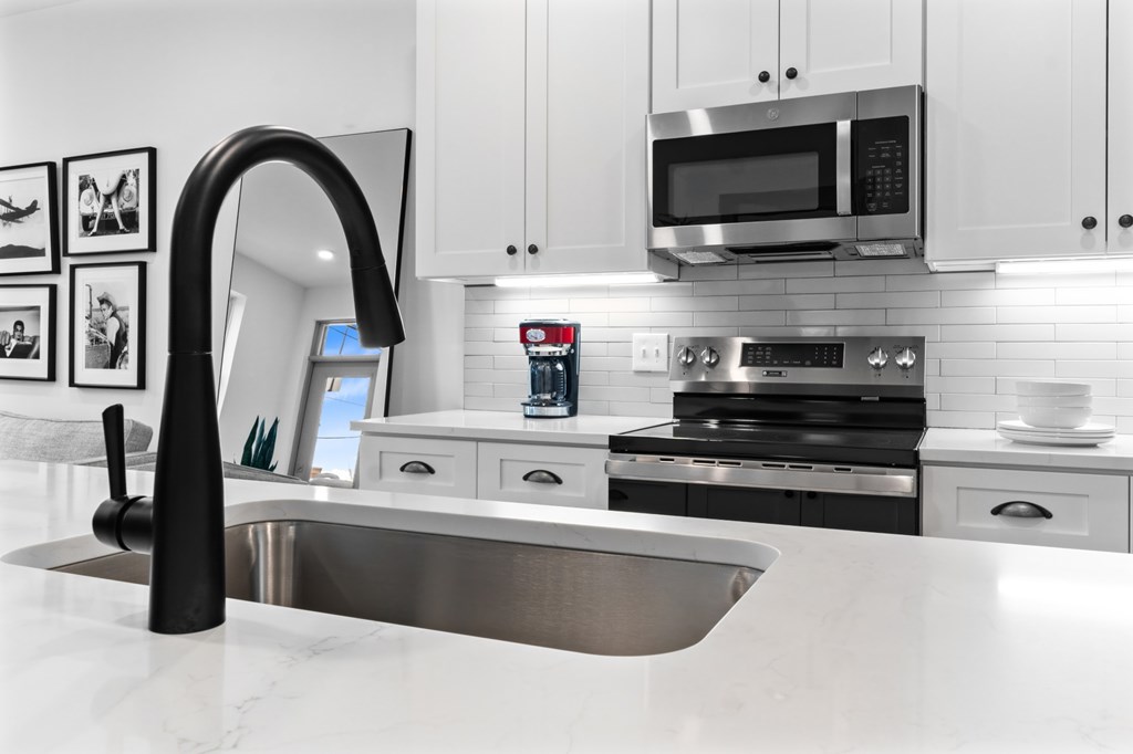 A modern kitchen with a stainless steel sink and white cabinets. at The Ridge Apartments, Ohio, 45213