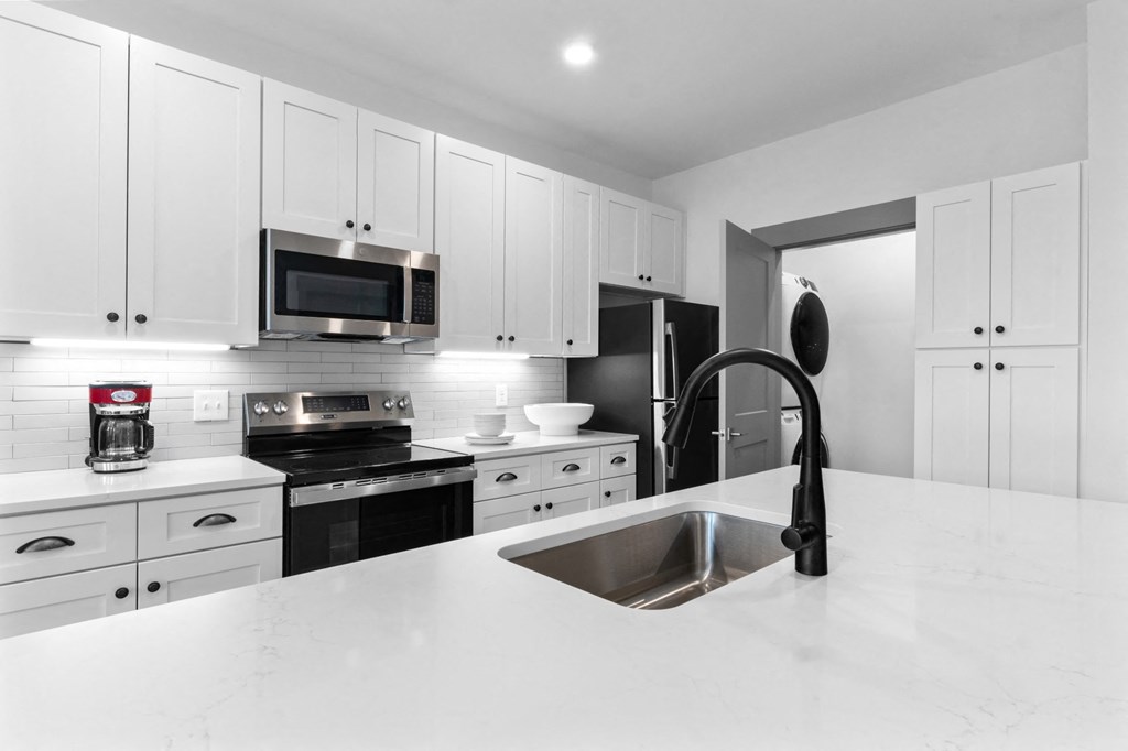 A modern kitchen with white cabinets and black appliances. at The Ridge Apartments, Cincinnati, OH, 45213