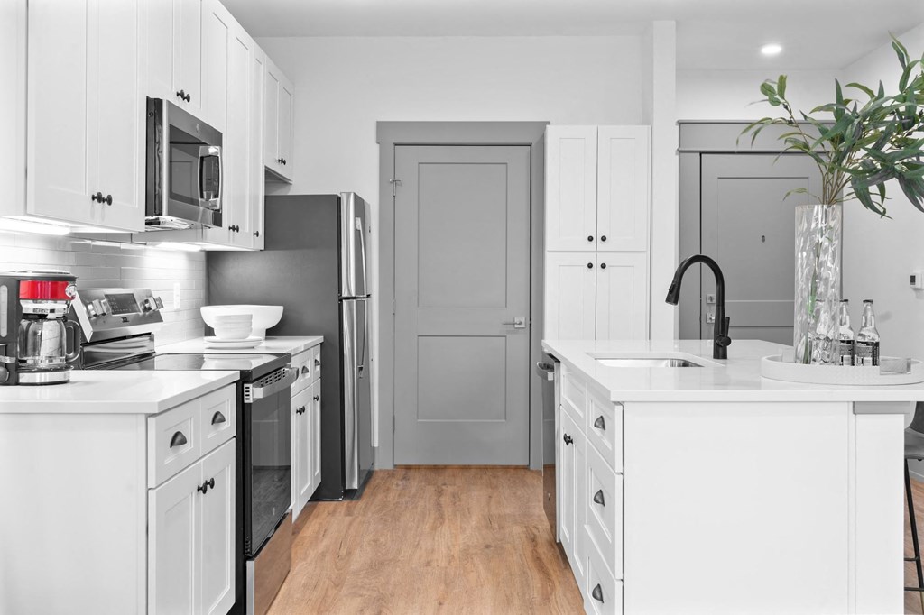 A modern kitchen with white cabinets and a wooden floor. at The Ridge Apartments, Cincinnati, OH