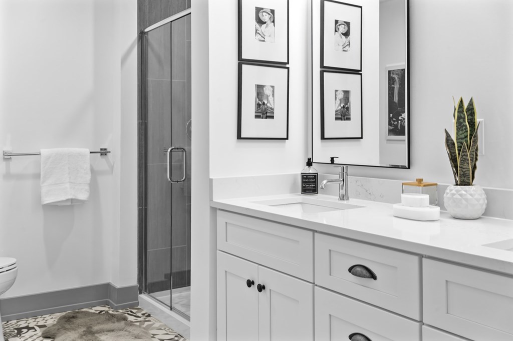A bathroom with a white sink, a mirror, and a glass shower door. at The Ridge Apartments, Cincinnati, Ohio