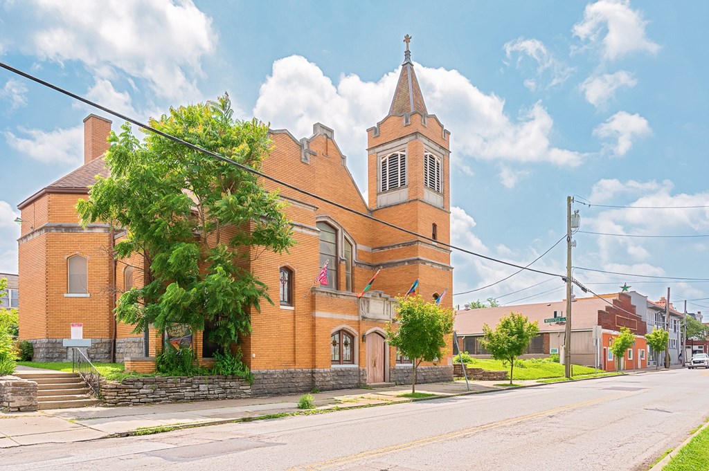 A church with a steeple and a cross on top is surrounded by a brick wall and trees. at The Ridge Apartments, Ohio