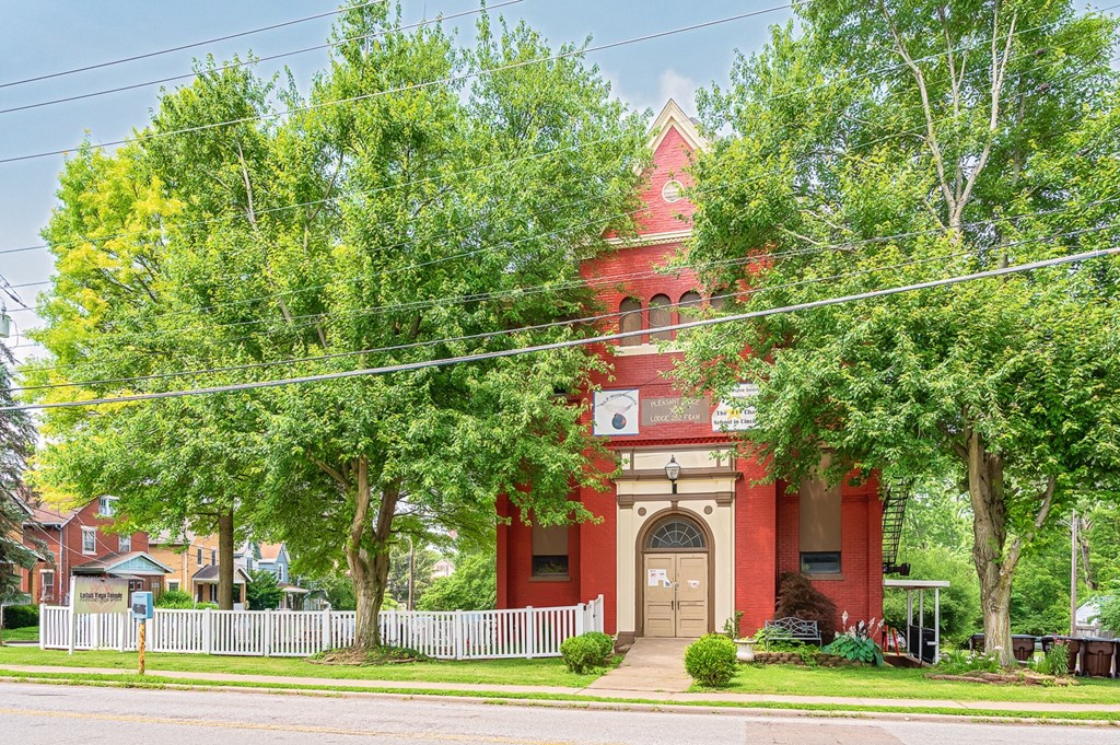 A red brick building with a white clock tower stands in front of a green tree. at The Ridge Apartments, Cincinnati