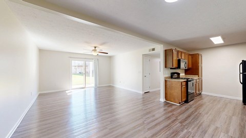 A spacious living room with a kitchenette and sliding glass doors.