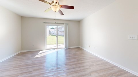 A room with a ceiling fan and sliding glass doors.