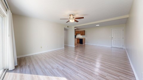 A room with a ceiling fan and light, hardwood floors, and a white door.