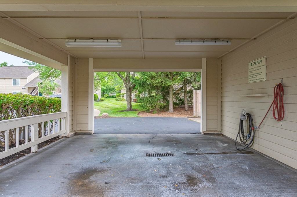 an empty garage with a driveway and trees in the background