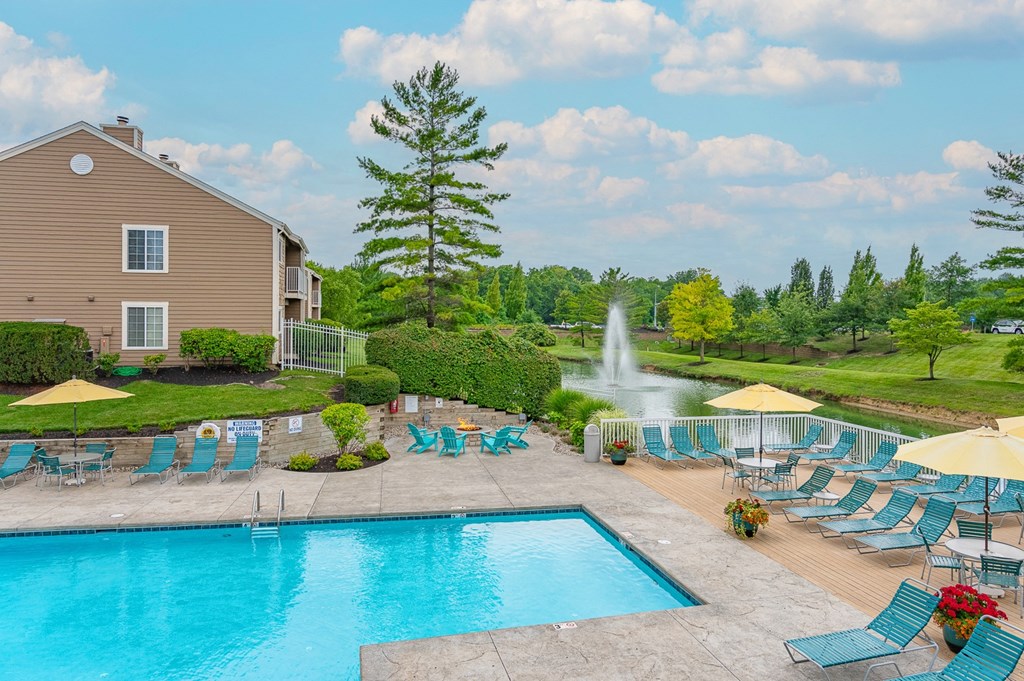 a swimming pool with chaise lounge chairs and umbrellas next to a house with a