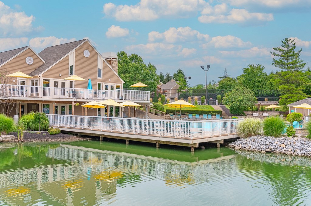 a house on the water with a large deck with umbrellas