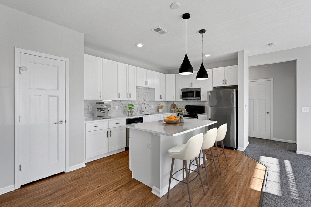 a large white kitchen with an island and white chairs at Monmouth Row Apartments, Newport, Kentucky