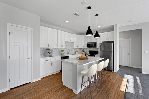 a large white kitchen with an island and white chairs