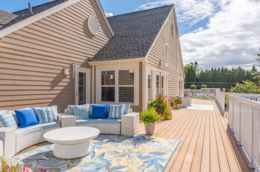 A house with a wooden deck and a white couch with blue pillows.