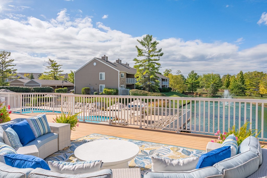 A house with a pool and a deck with a white table and chairs.