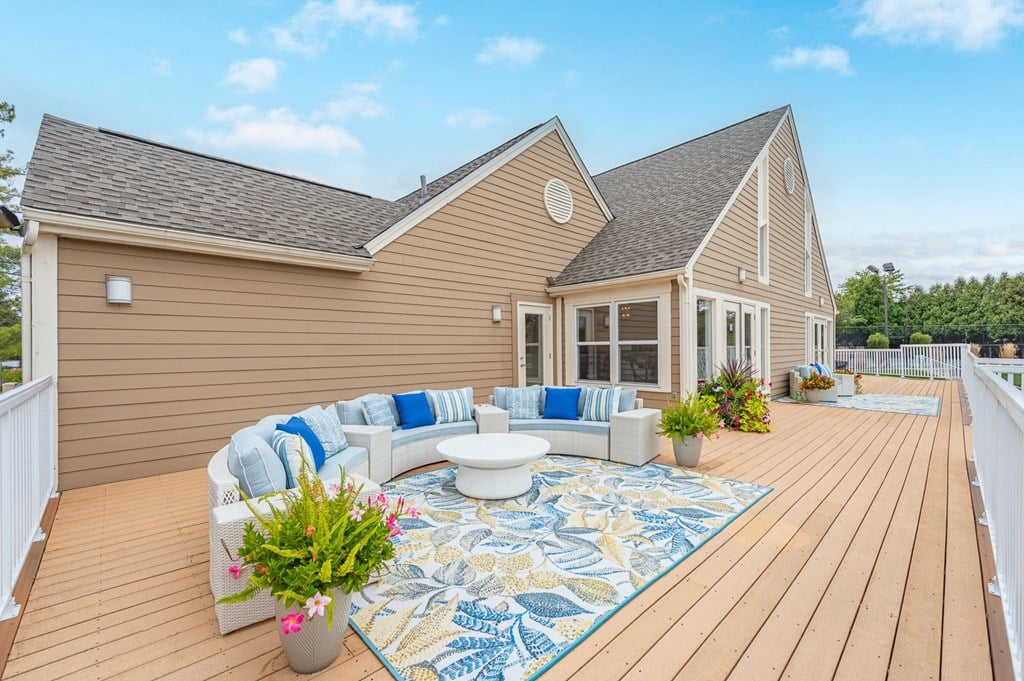 A house with a deck and a white sofa with blue cushions.