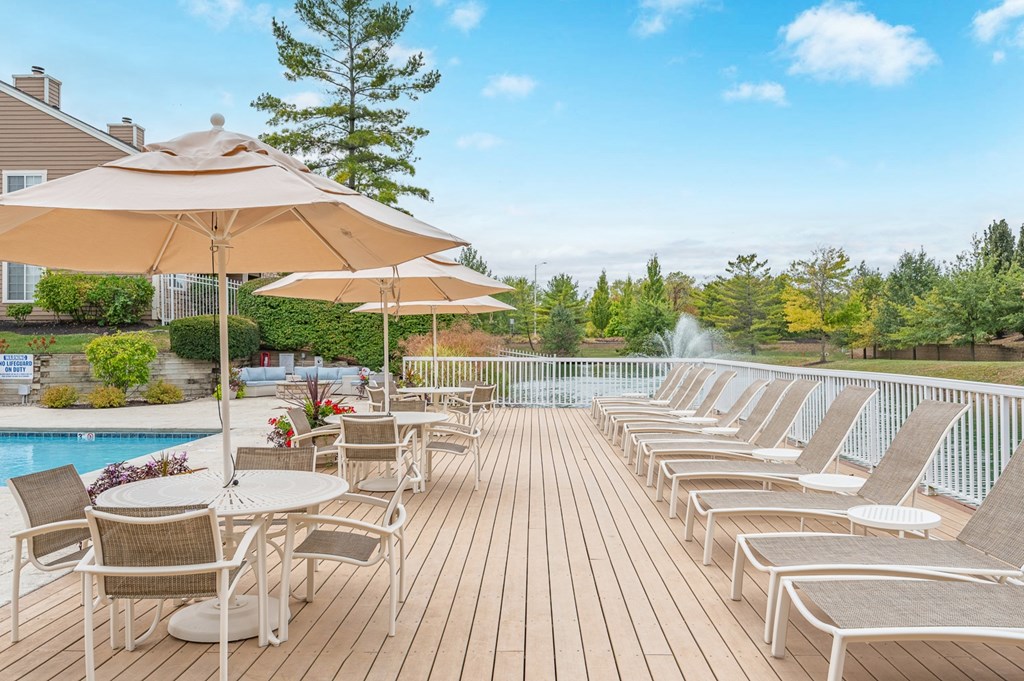 A poolside deck with chairs and umbrellas overlooking a pool.