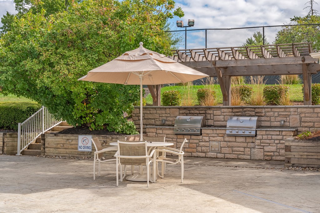 A patio with a table, chairs and an umbrella.