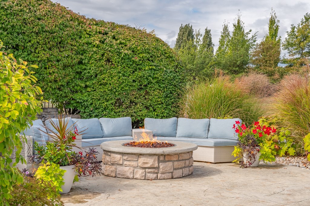 A backyard with a stone fire pit and a blue couch.