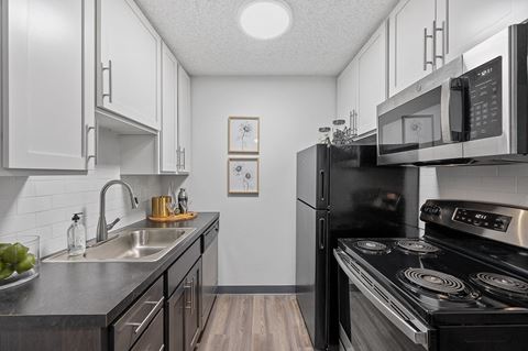 a kitchen with white cabinetry and black appliances  at Timber Glen Apartments, Ohio