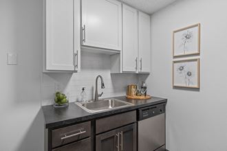 a kitchen with white cabinets and a stainless steel sink  at Timber Glen Apartments, Batavia