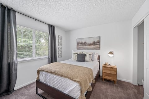 a bedroom with a bed and a nightstand  at Timber Glen Apartments, Batavia, 45103