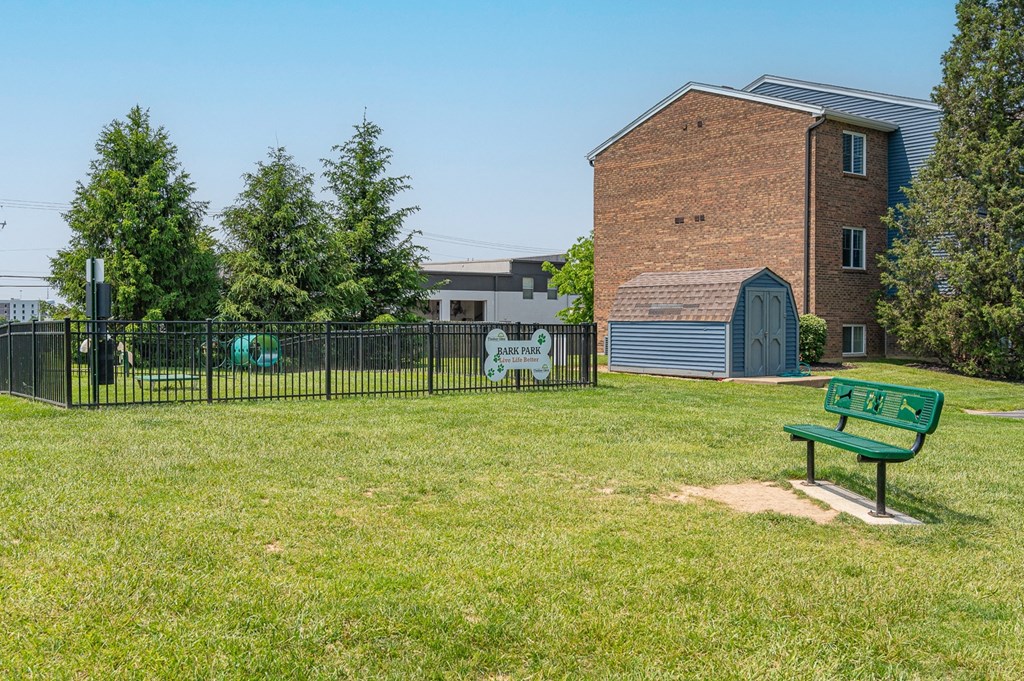a park with a bench in front of a fence and a building