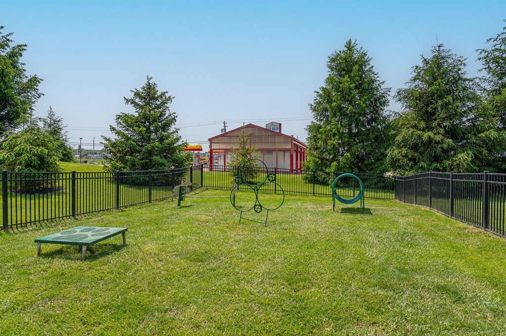 a yard with a swing set and a fence with a house in the background