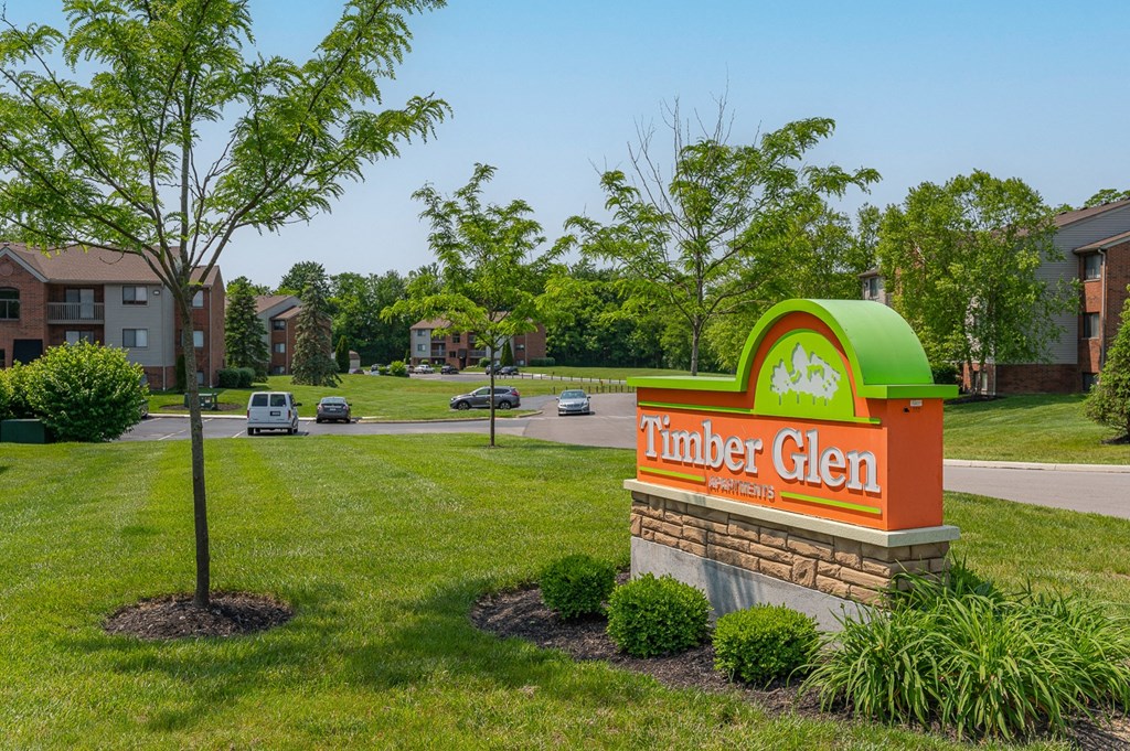 a sign for the thunder glen apartment building with a street in the background