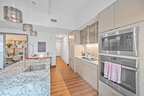 A modern kitchen with a stainless steel oven and wooden floors.