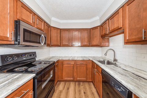 A kitchen with wooden cabinets and a black stove top oven.