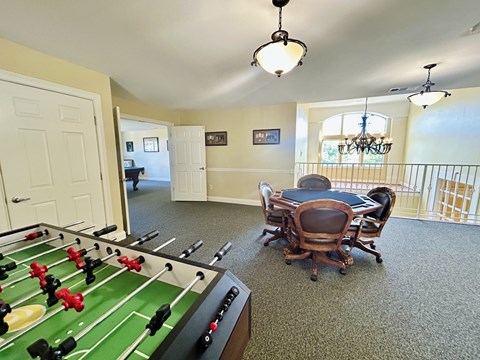 A foosball table is in the middle of a room with a dining table and chairs.