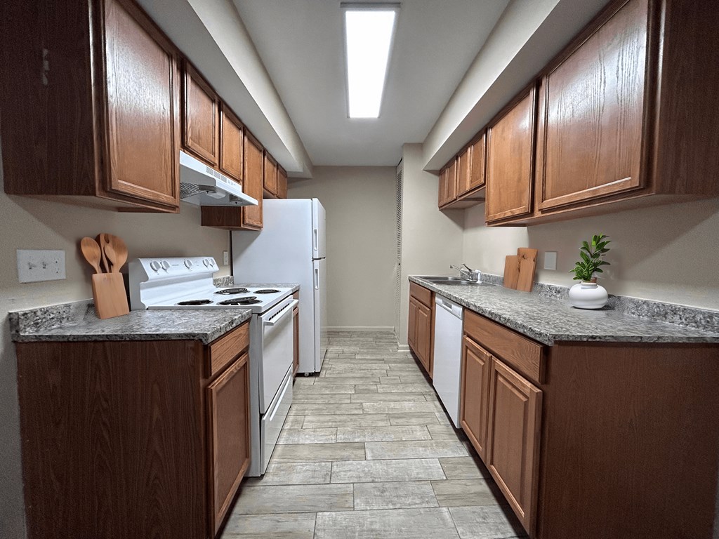 a kitchen with wood cabinets and white appliances and tile flooring
