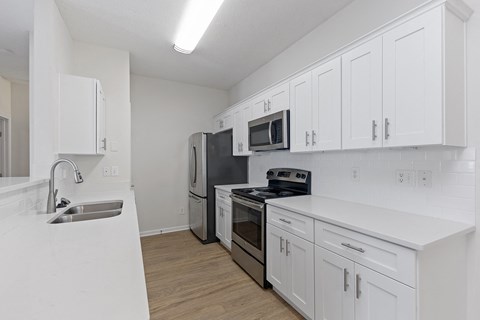 a white kitchen with stainless steel appliances and white cabinets