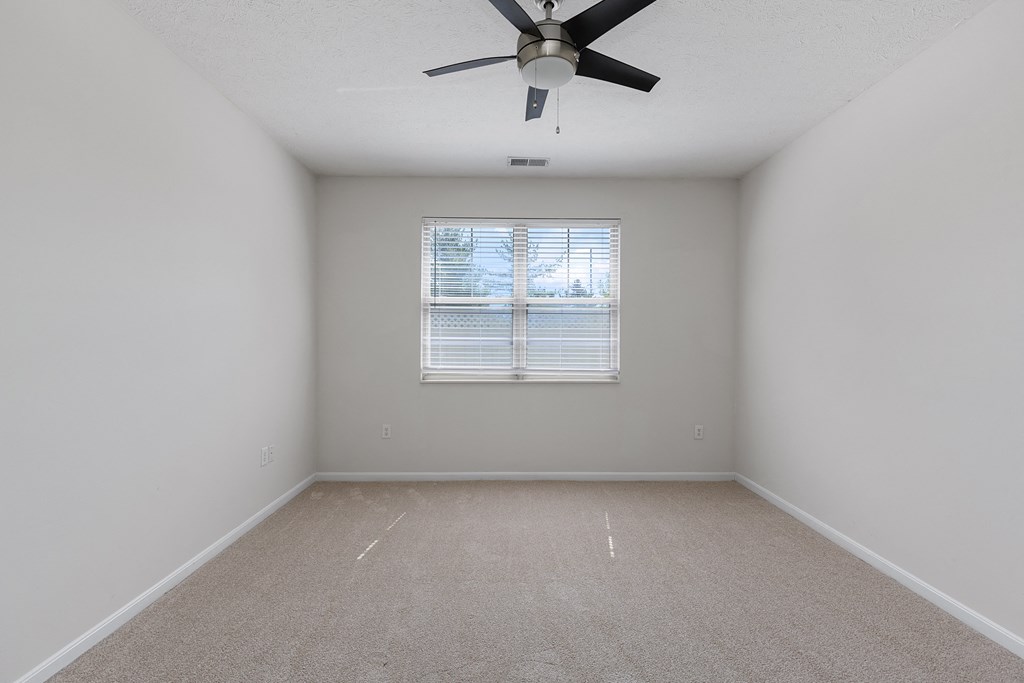 an empty room with a ceiling fan and a window