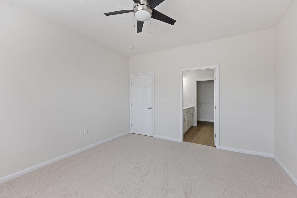 an empty living room with a ceiling fan