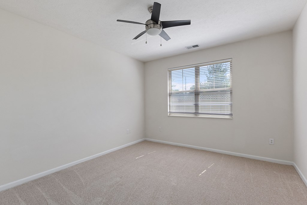 an empty room with a ceiling fan and a window